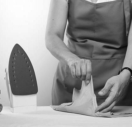 Woman in blue apron folding an ironed green shirtOther relates images: